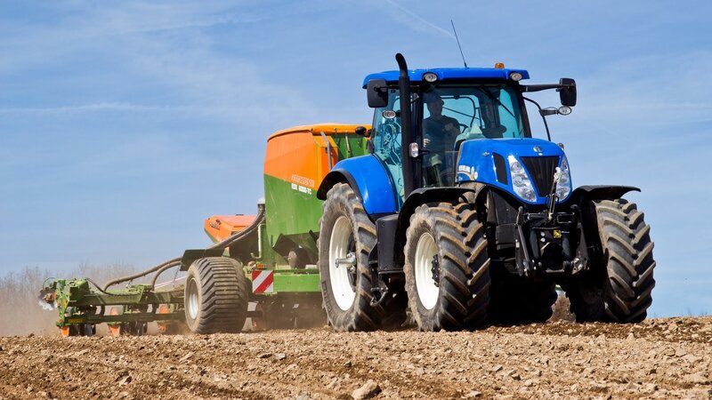 Blue Tractor Plowing Field