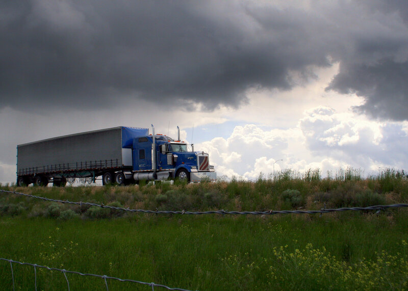 Blue truck on a hill under stormy sky