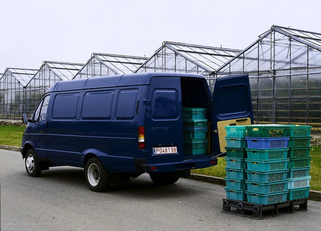 Blue van with crates outside greenhouse