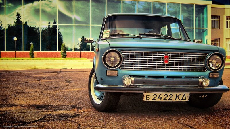 Blue vintage car in front of glass building