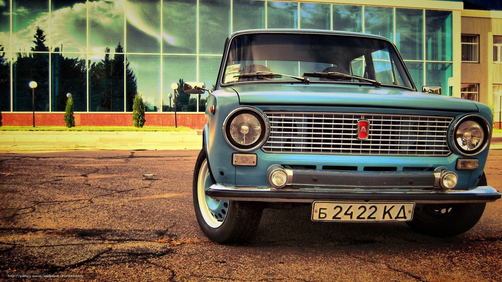 Blue vintage car in front of glass building