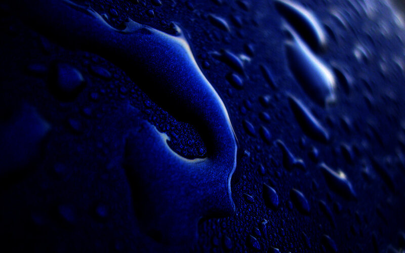 Blue water droplets on dark surface