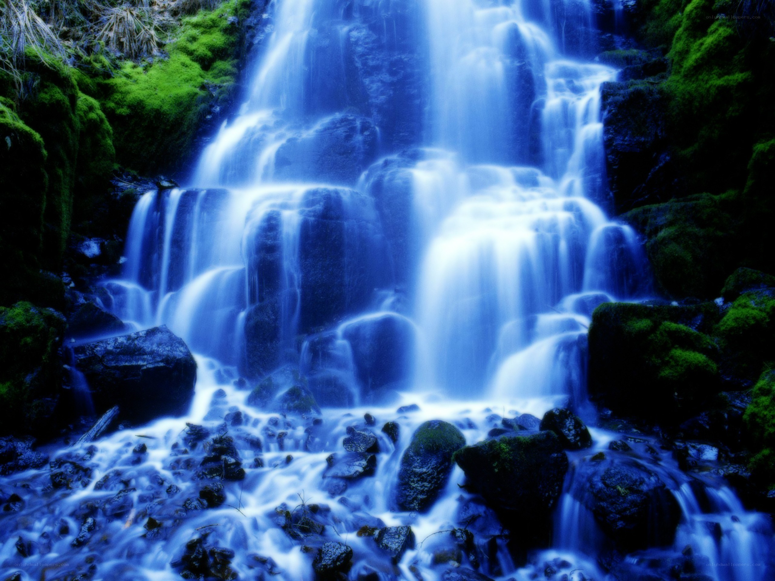 Blue waterfall cascading over mossy rocks