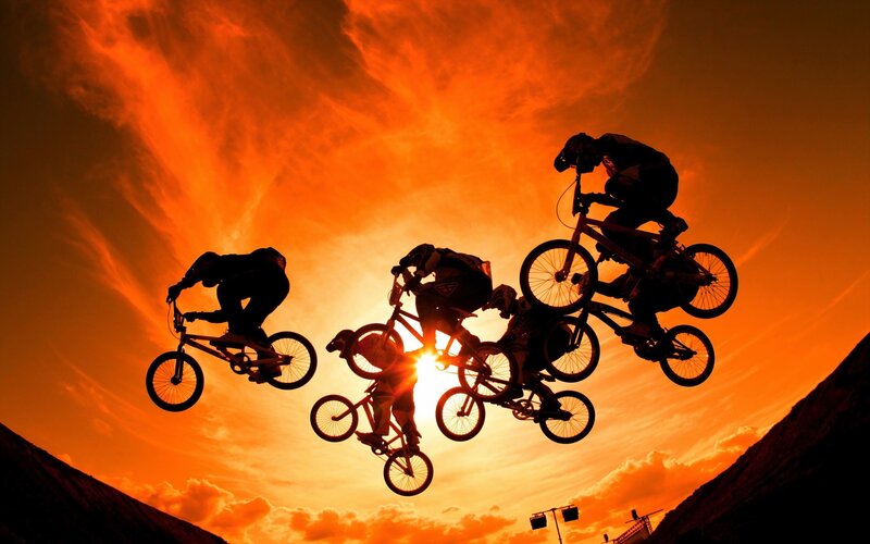 BMX riders in sunset silhouettes