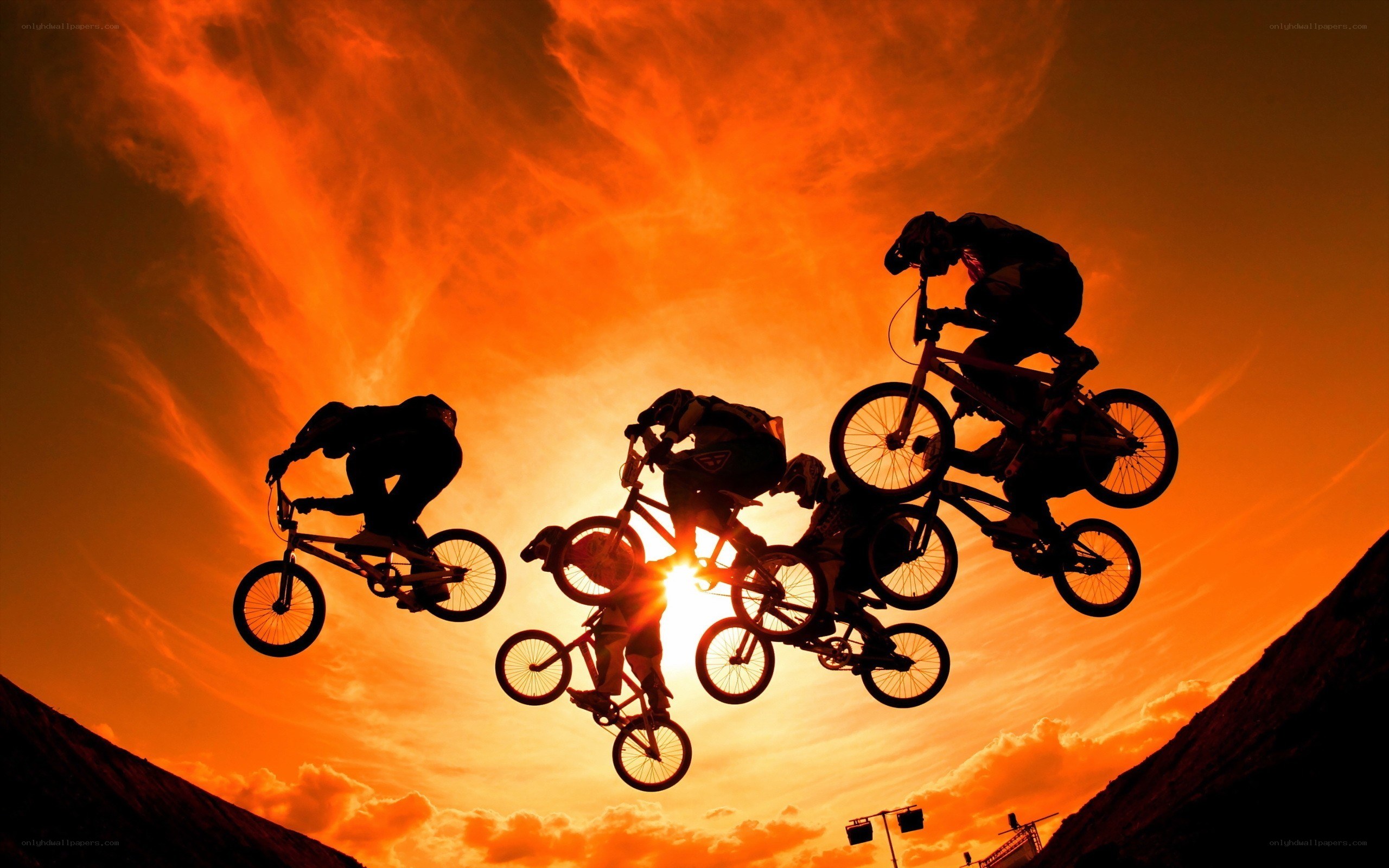 BMX riders in sunset silhouettes