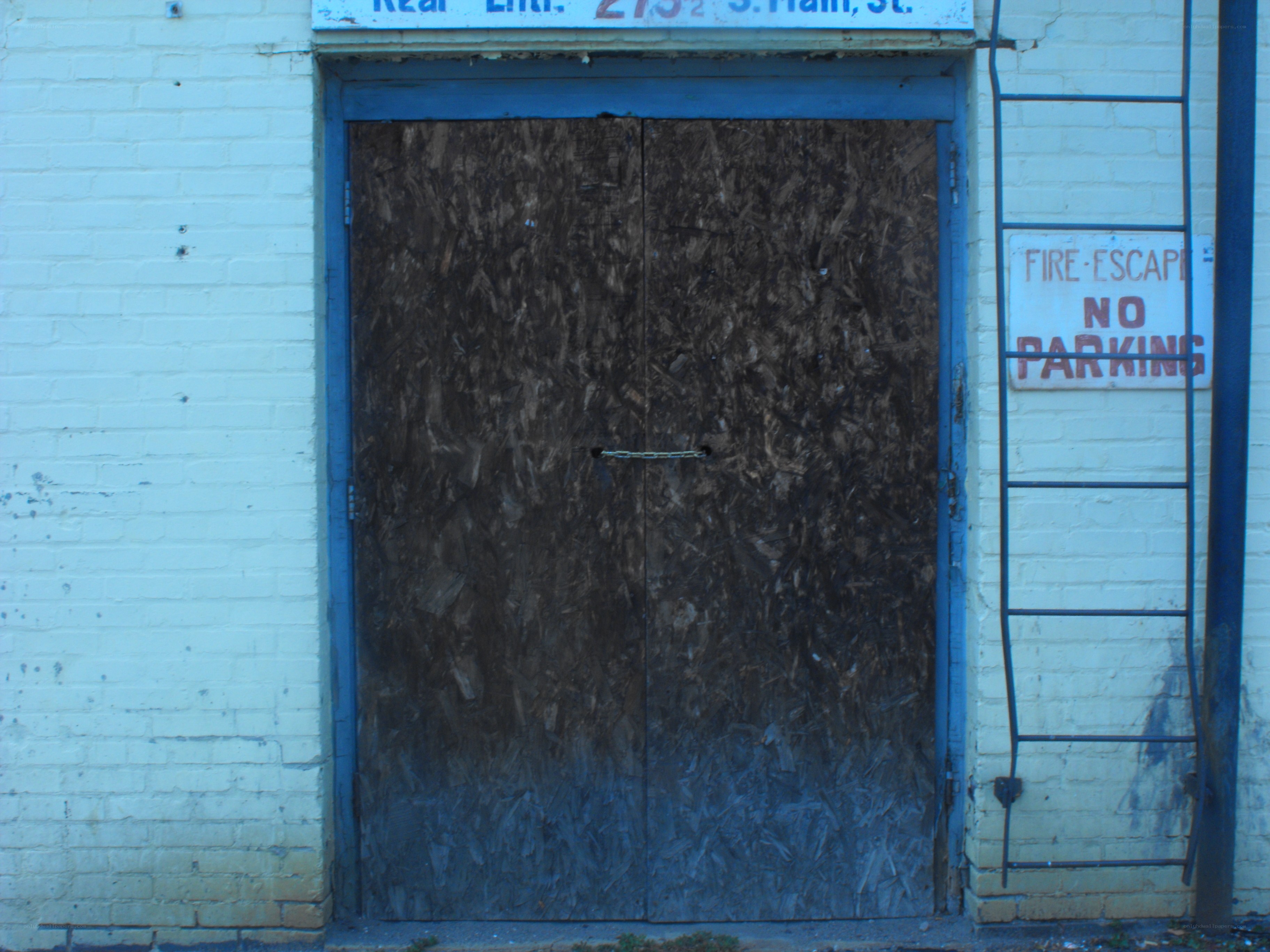 boarded-up door with fire escape sign