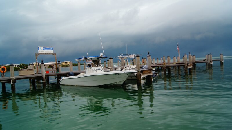 Boat docked at pier under stormy sky