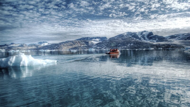 Boat near icebergs in fjord