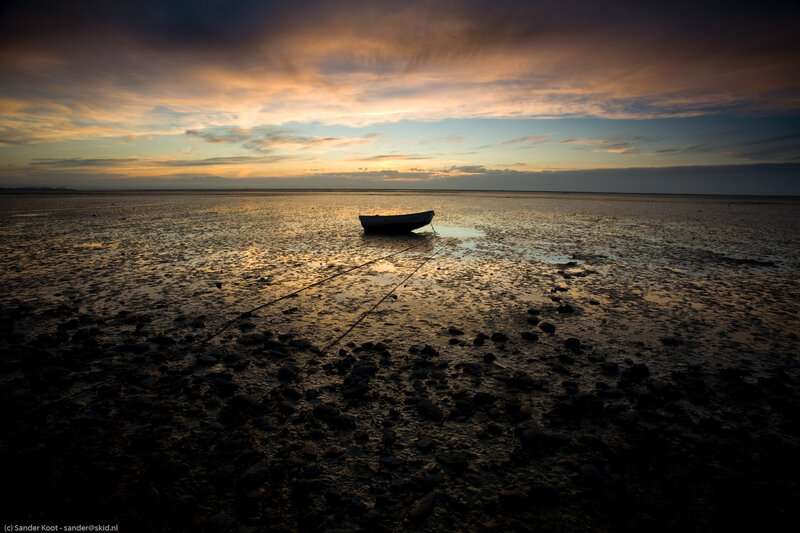 Boat on a muddy shore at sunset