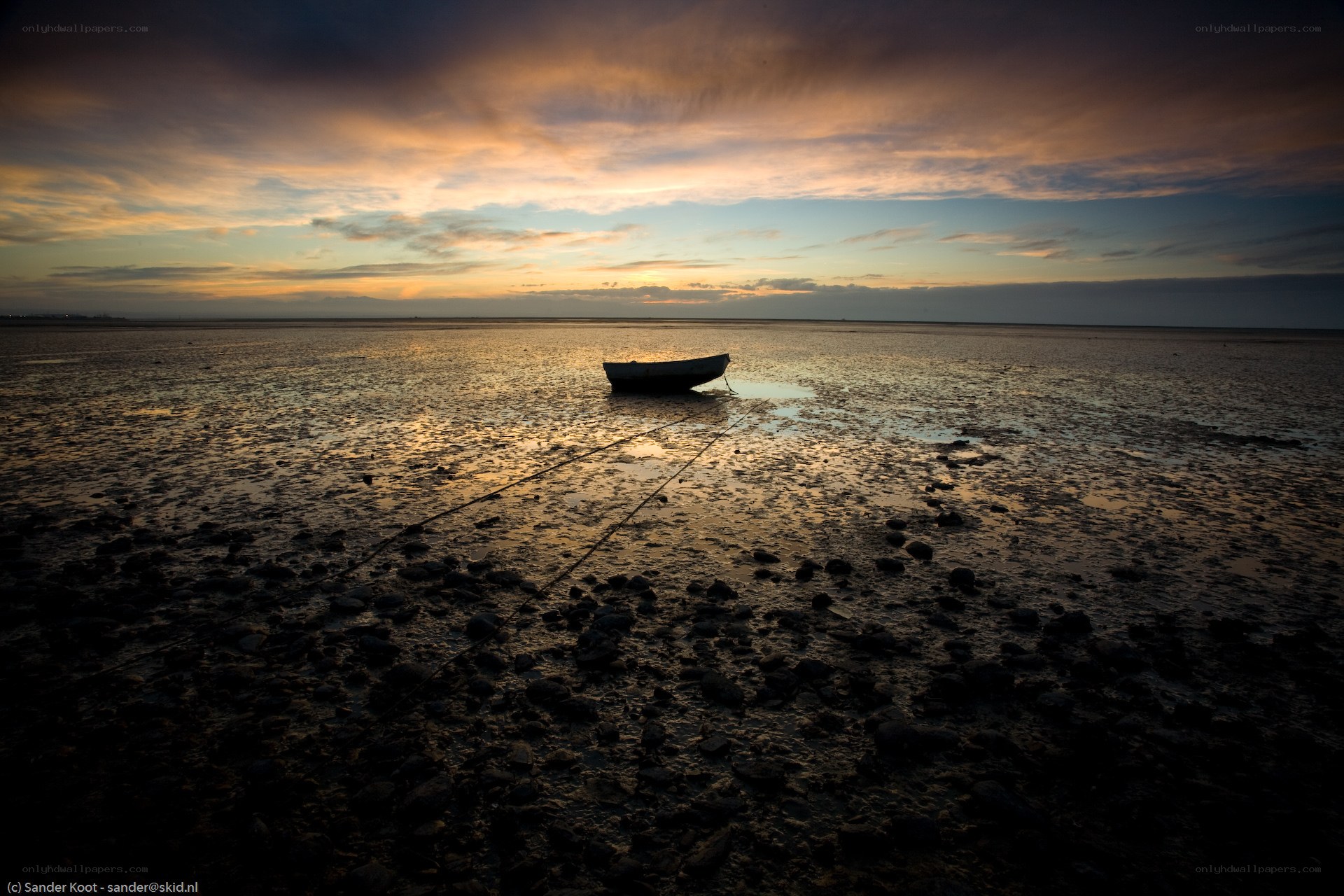 Boat on a muddy shore at sunset