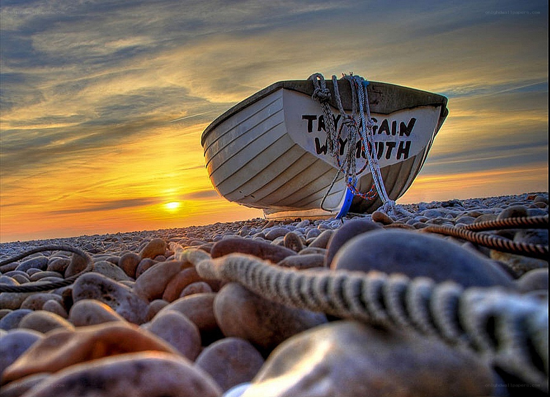 Boat on a pebble beach at sunset