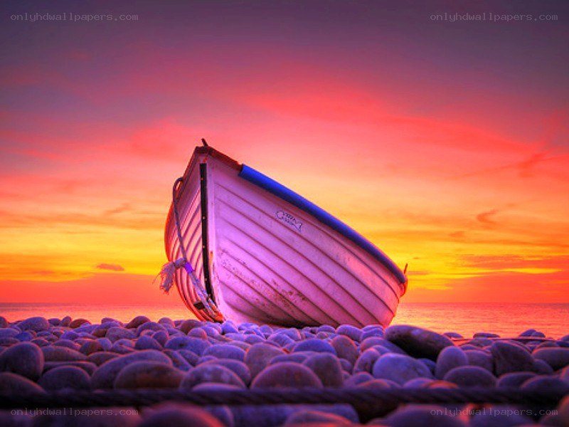 Boat on a pebble beach at sunset