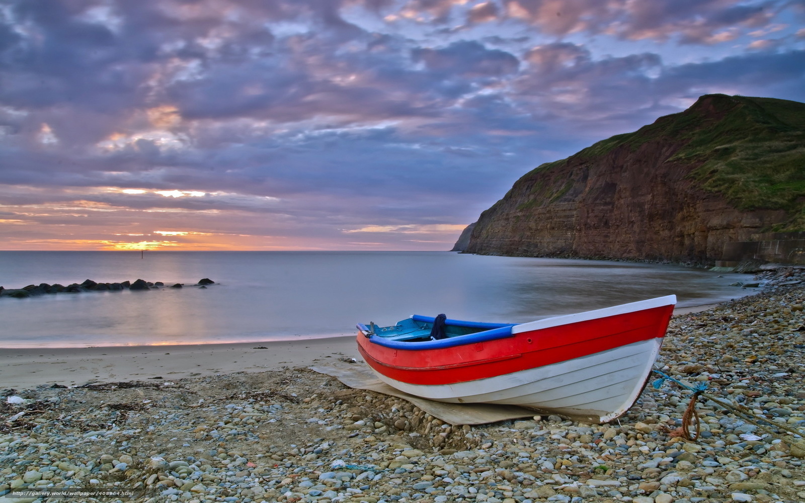 Boat on a pebble beach at sunset