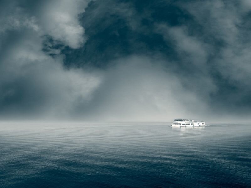 Boat on calm sea under stormy sky