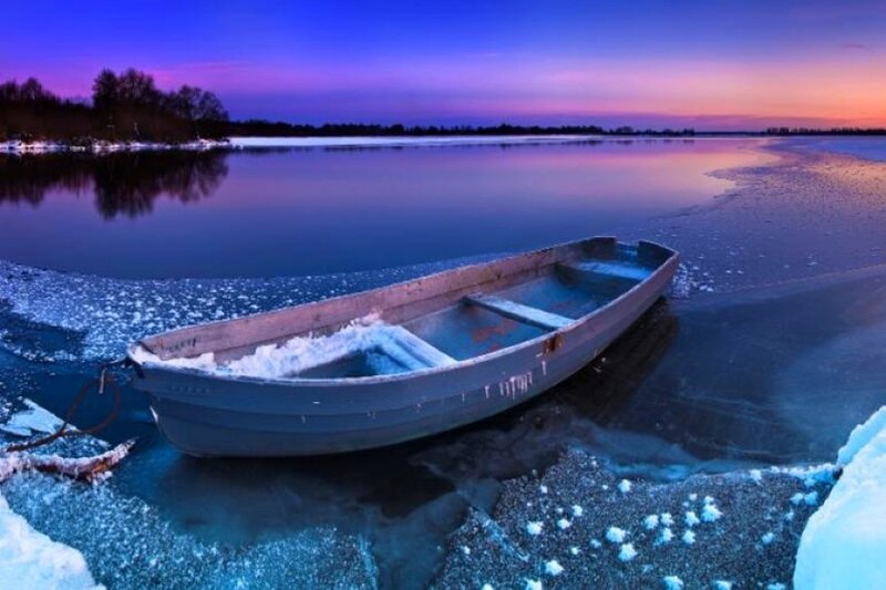 Boat on frozen lake at dusk
