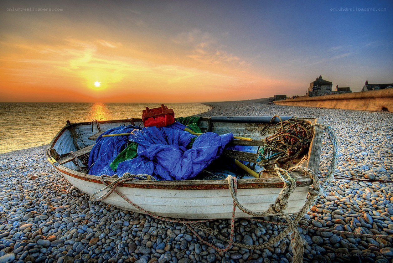 Boat on pebble beach at sunset