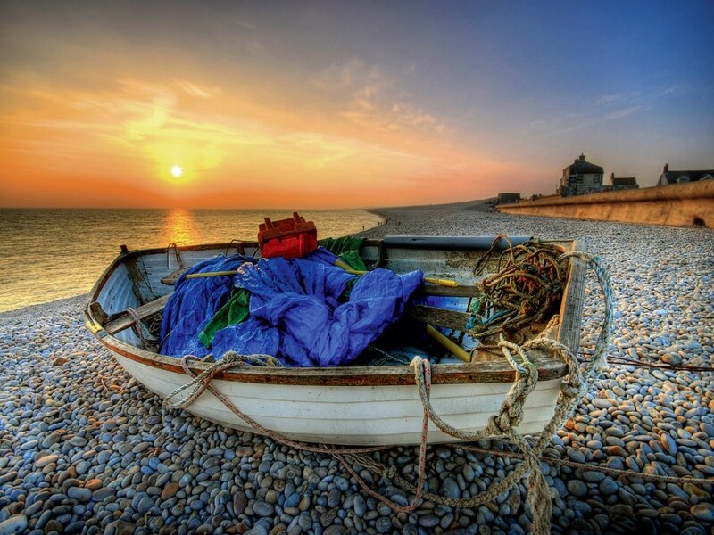 Boat on pebble beach at sunset