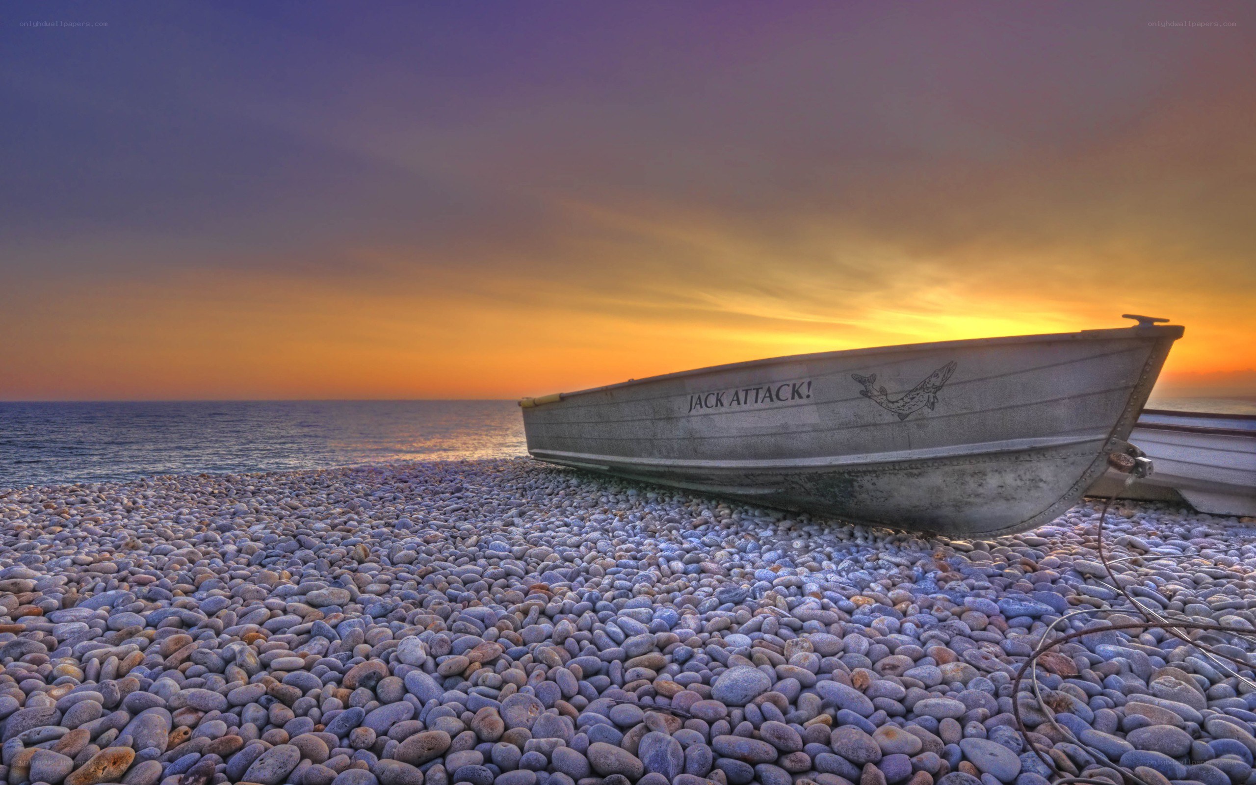 Boat on pebble beach at sunset