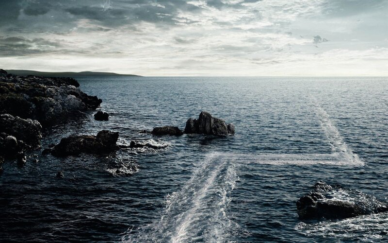 Boat wake near rocky coast