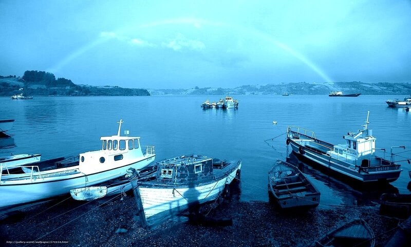Boats at a harbor with a rainbow