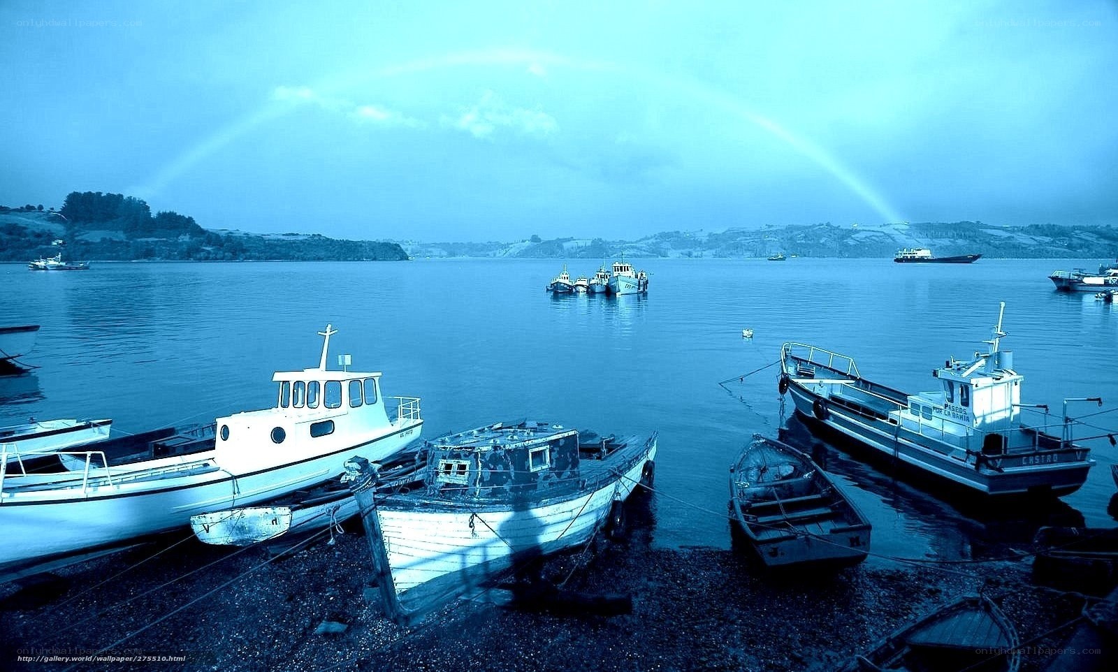 Boats at a harbor with a rainbow