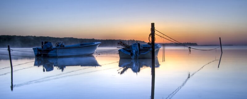 Boats at dawn on a misty lake