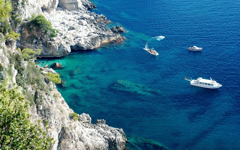 Boats near rocky coastline