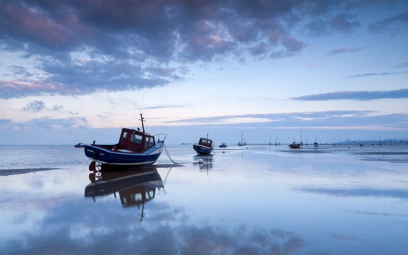 Boats on a calm beach at dusk