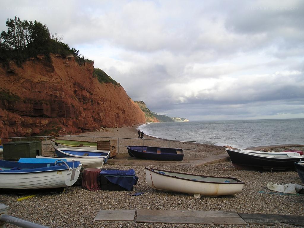 Boats on a pebble beach by cliffs