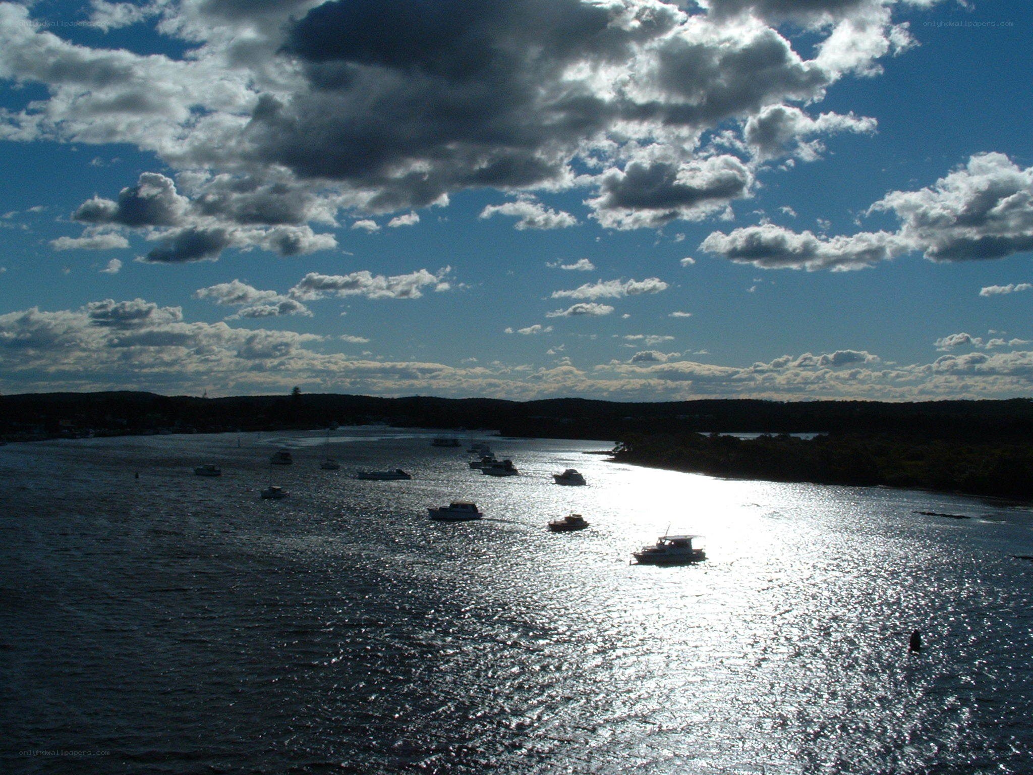 Boats on a river under cloudy sky