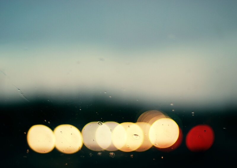 Bokeh lights through rain-streaked glass