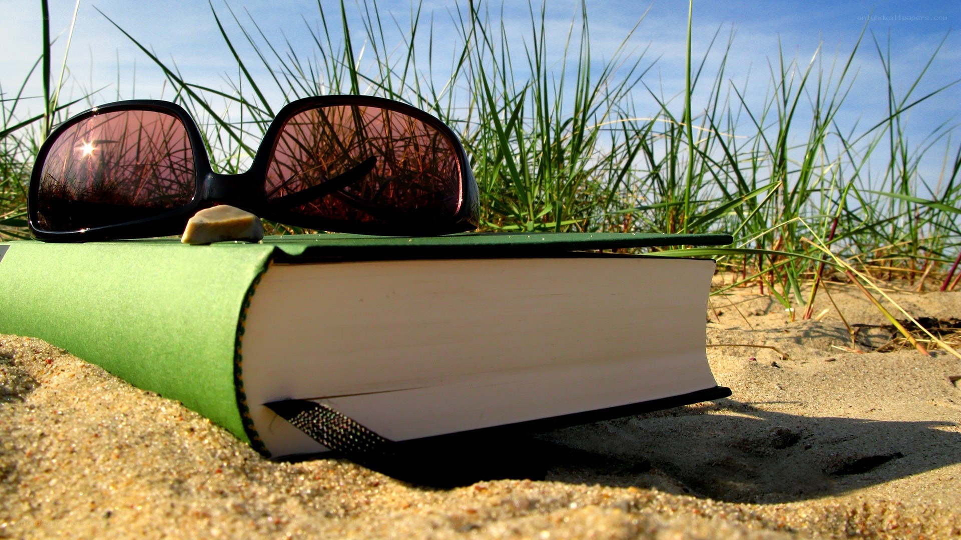 Book and sunglasses on the beach
