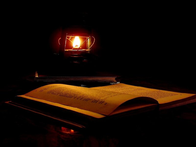 book illuminated by lantern
