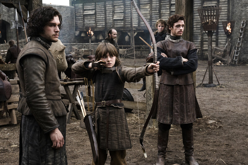 Boy aiming a bow in medieval setting