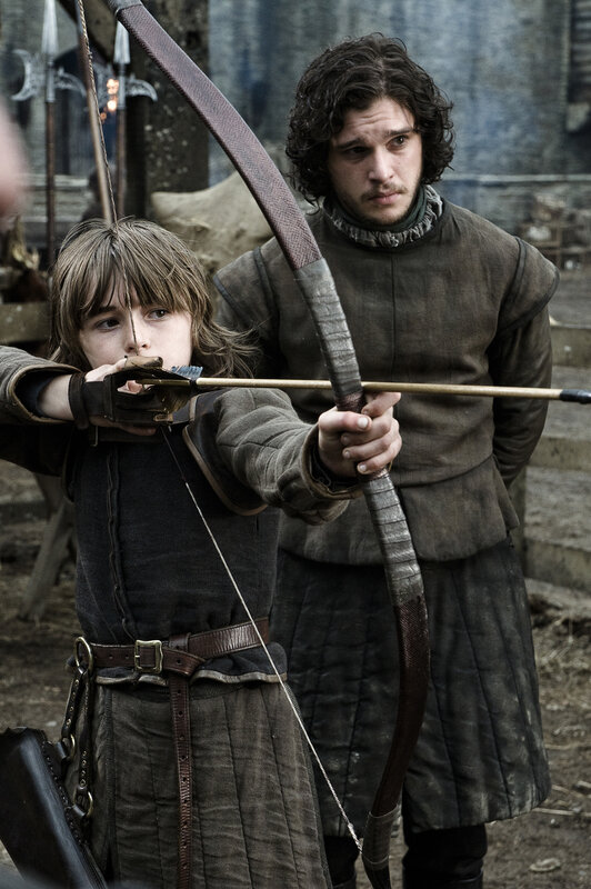 boy aiming bow with man behind