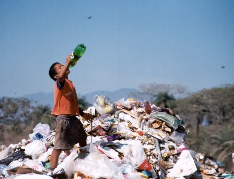 Boy drinking from bottle at dump