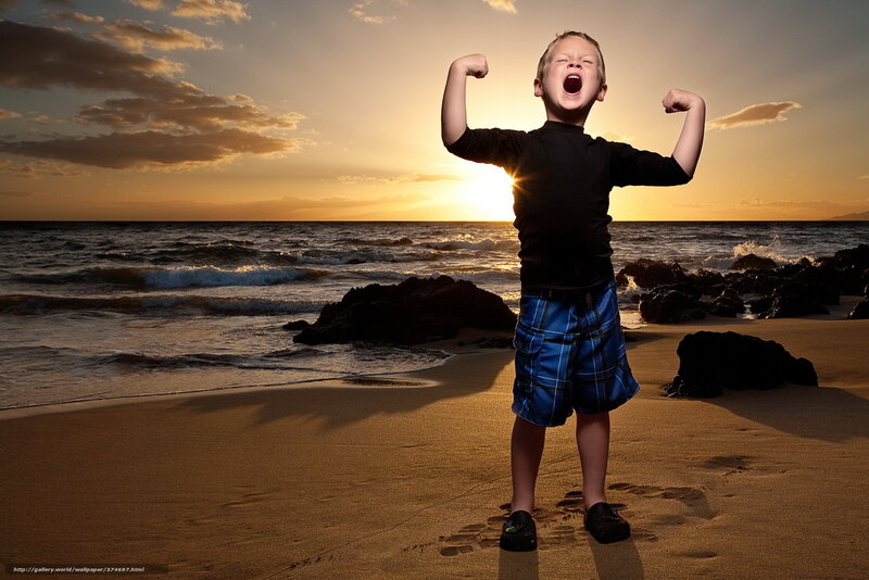 Boy flexing on beach at sunset
