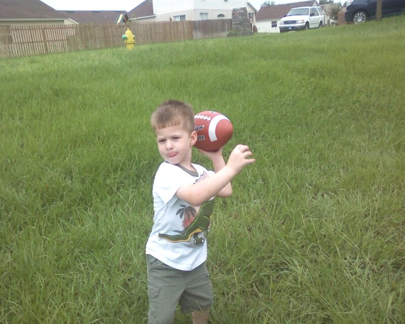 boy holding football in yard
