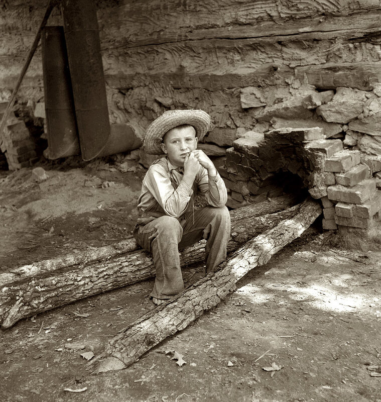 Boy in straw hat sitting on logs