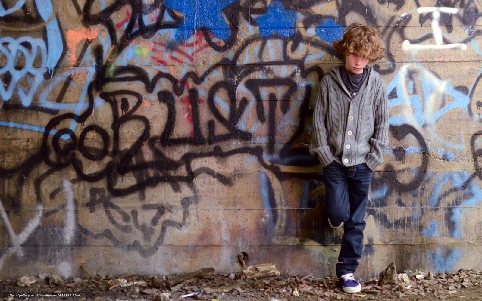 Boy leaning against graffiti wall