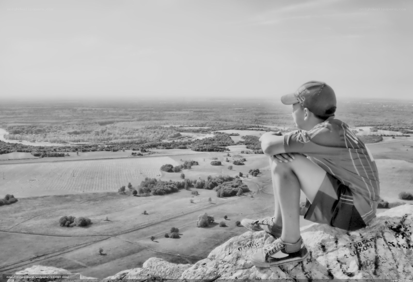 Boy on a cliff overlooking landscape