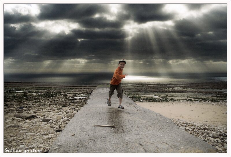 Boy on a pier under stormy sky