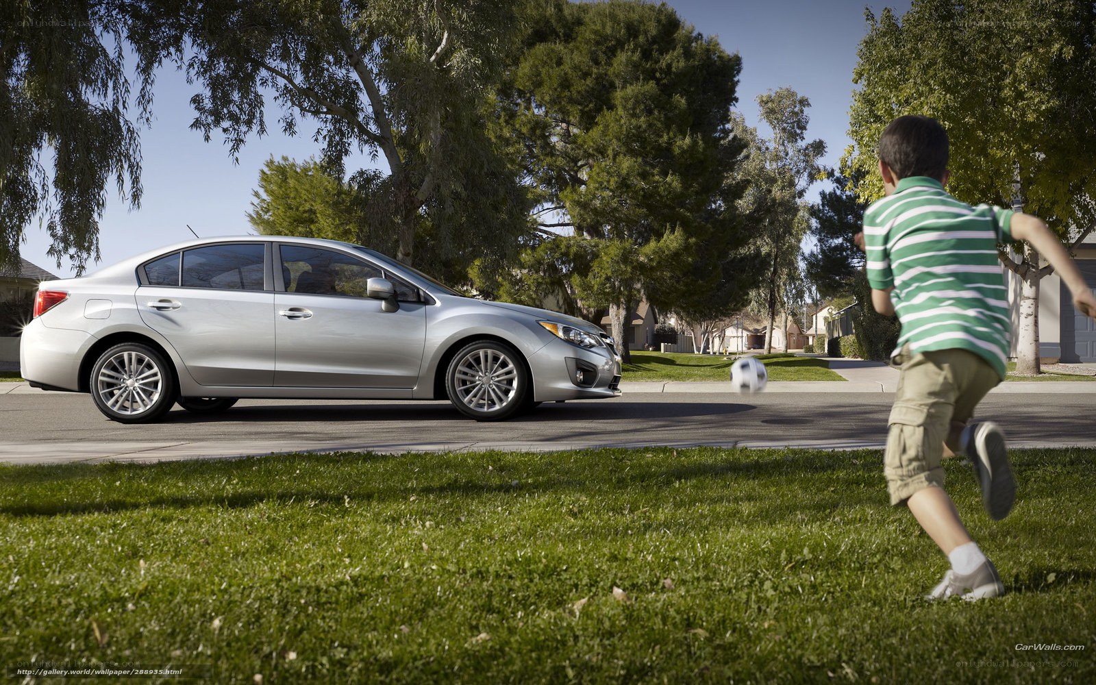 Boy playing soccer near car