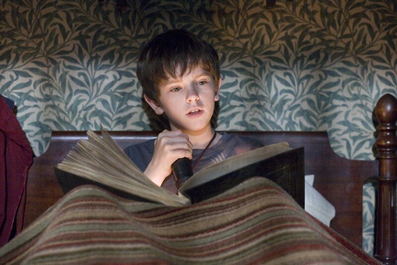 boy reading book in bed