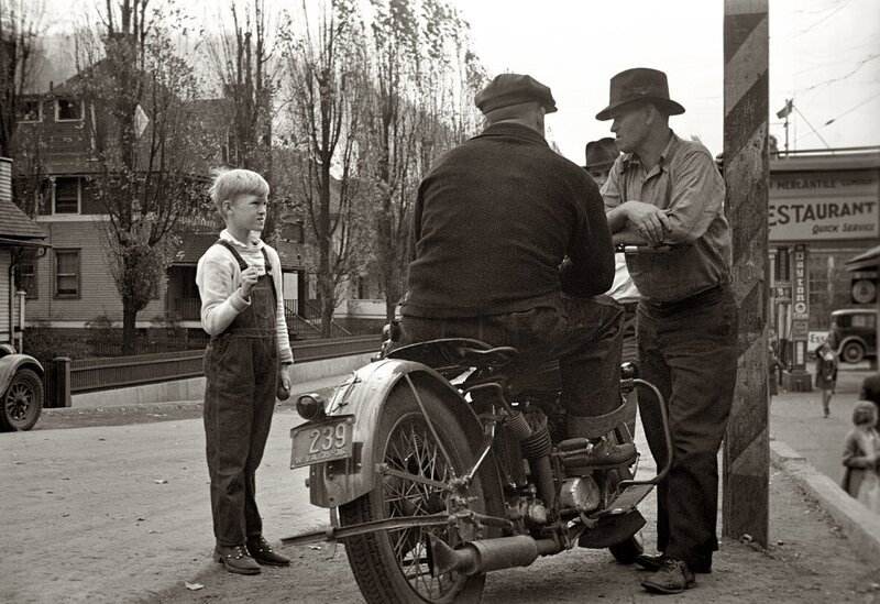 Boy talking to men by motorcycle