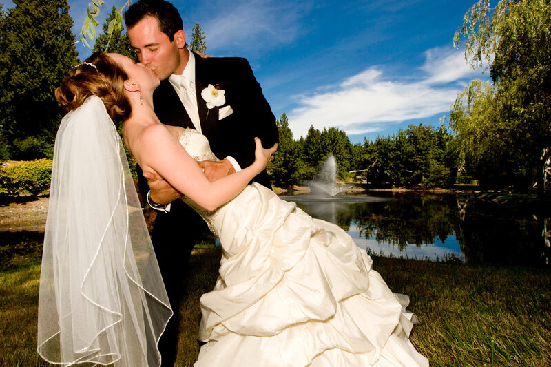 Bride and groom kiss by pond