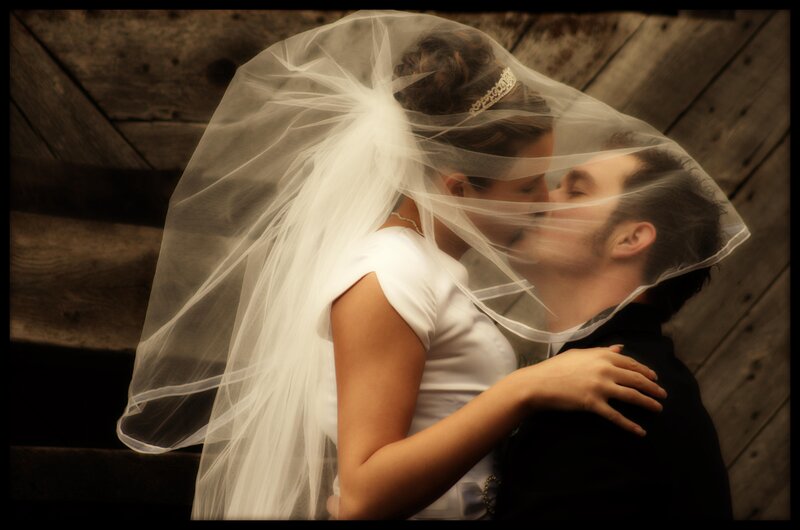 Bride and groom kissing under veil