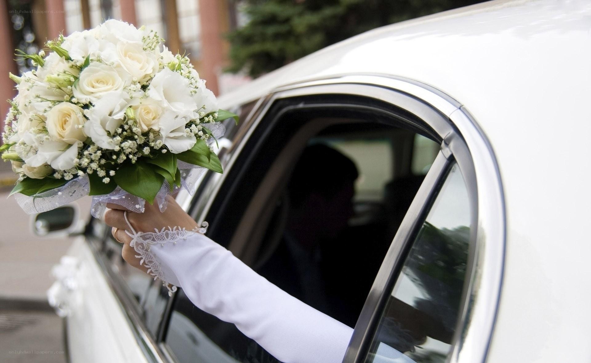 Bride holding bouquet by car