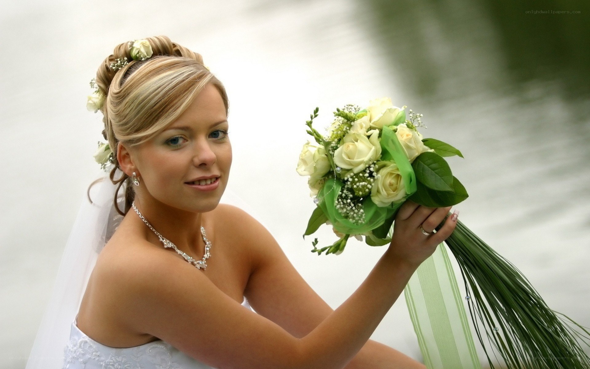 Bride with bouquet by water