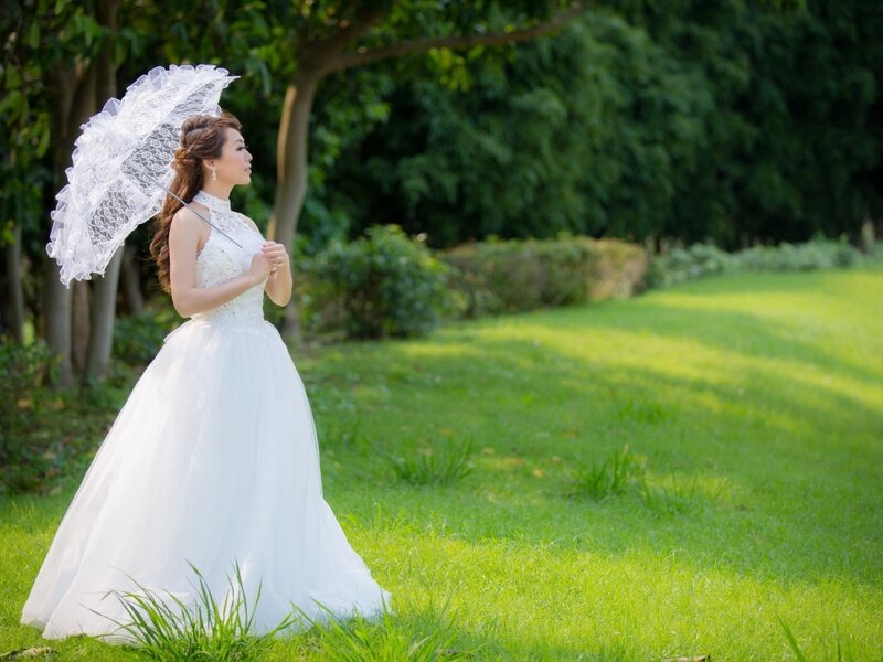 Bride with lace parasol in park